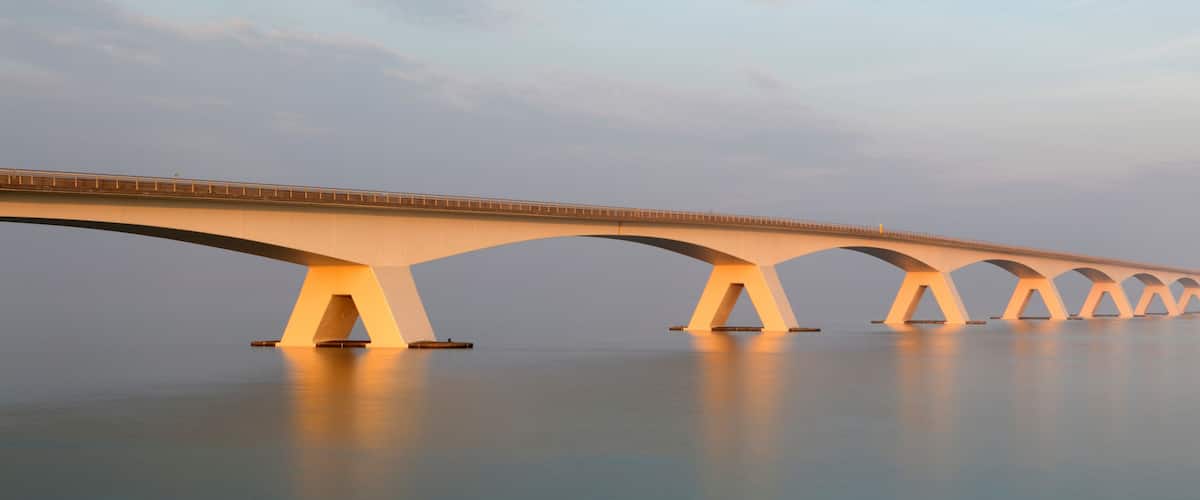 A long bridge with multiple arches spanning a calm body of water.