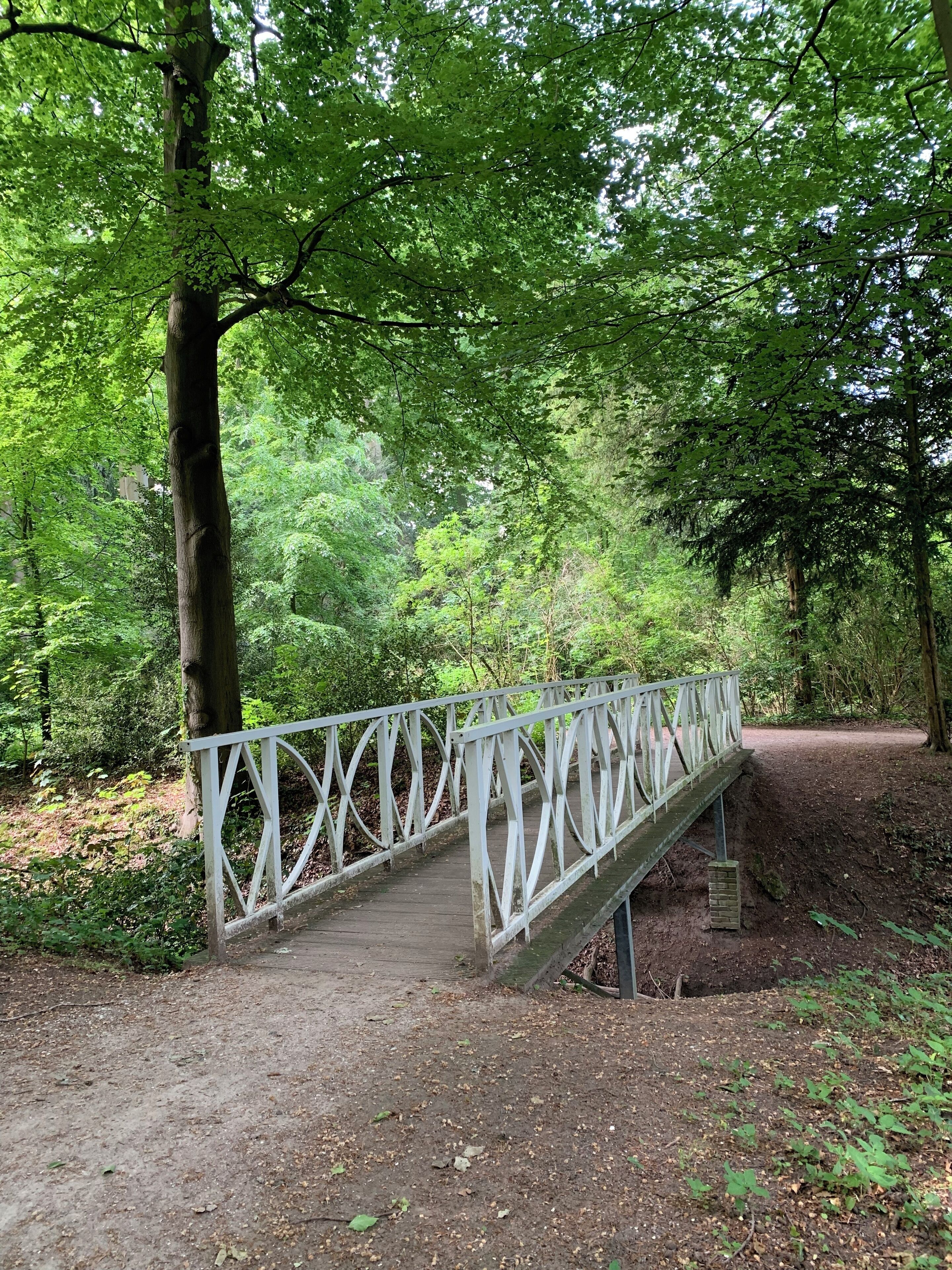 A white metal bridge in a forested area.