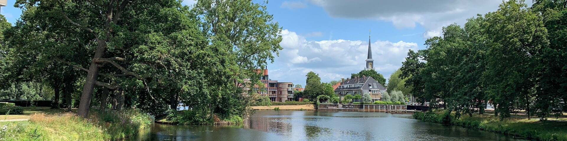 Un río con árboles e iglesia al fondo.