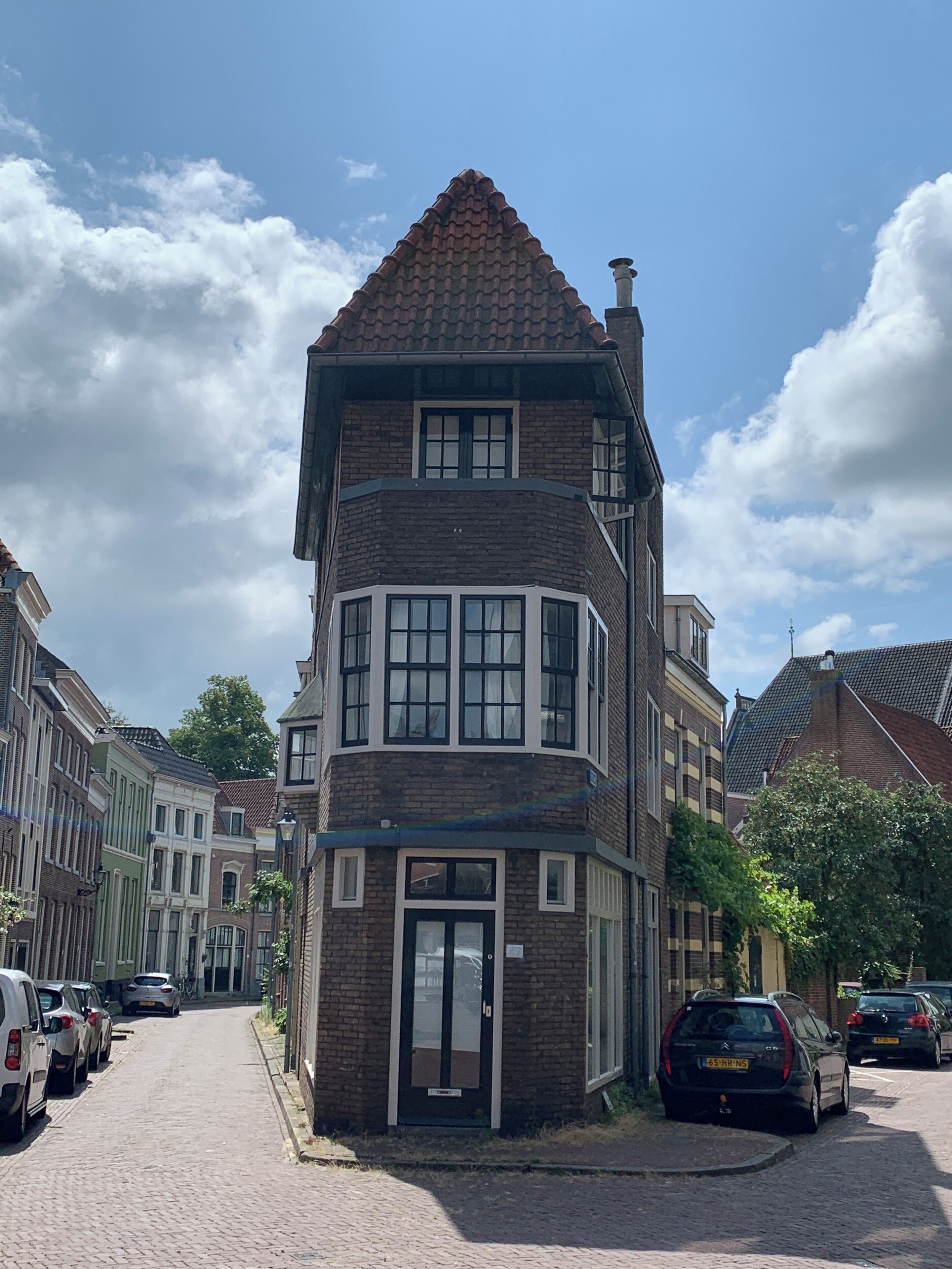 A corner building with a red-tiled roof, a bay window, and a door.