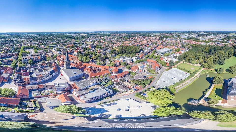 A panoramic view of a city with a prominent castle, dense residential areas, and surrounding greenery.
