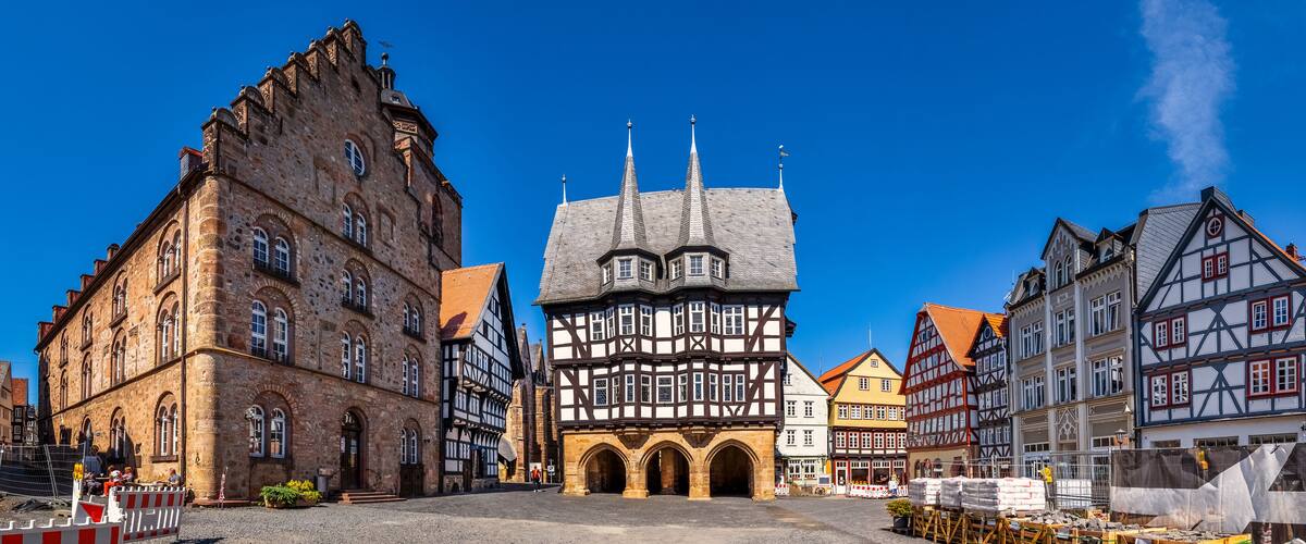 A historic town square with medieval buildings, including a prominent church with a spire.