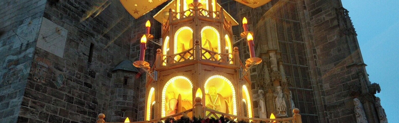 A traditional wooden Christmas market stall with a star-shaped lantern, set against a historic stone building with a tower.