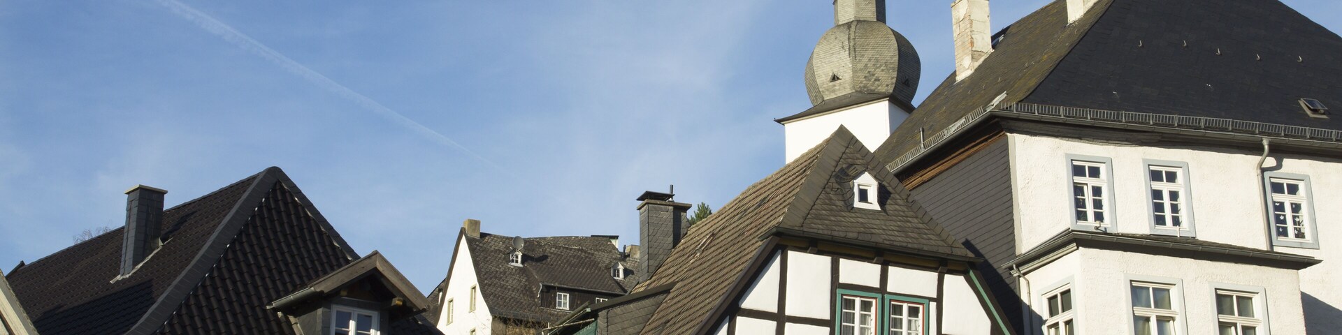 A traditional European town with half-timbered houses and a church with a spire.