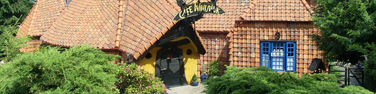 Une maison fantaisiste, dotée d’un toit à forte pente, d’une cheminée et d’une enseigne sur laquelle on peut lire « Café Winiewka ».