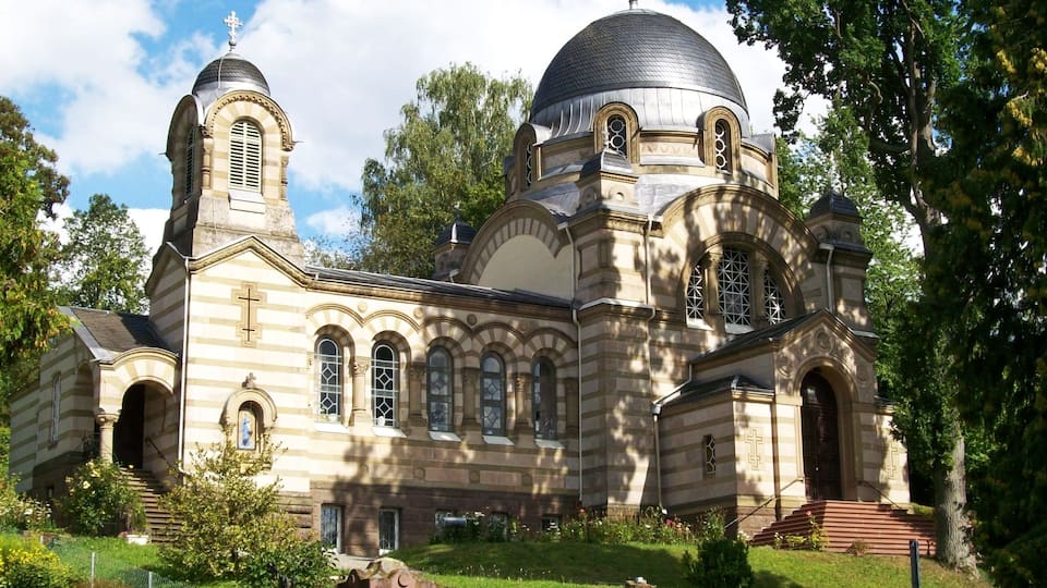 A historic church with a large dome, arched windows, and a cross on top.
