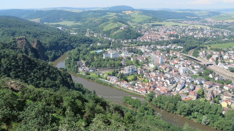 A river winding through a town surrounded by hills and forests.
