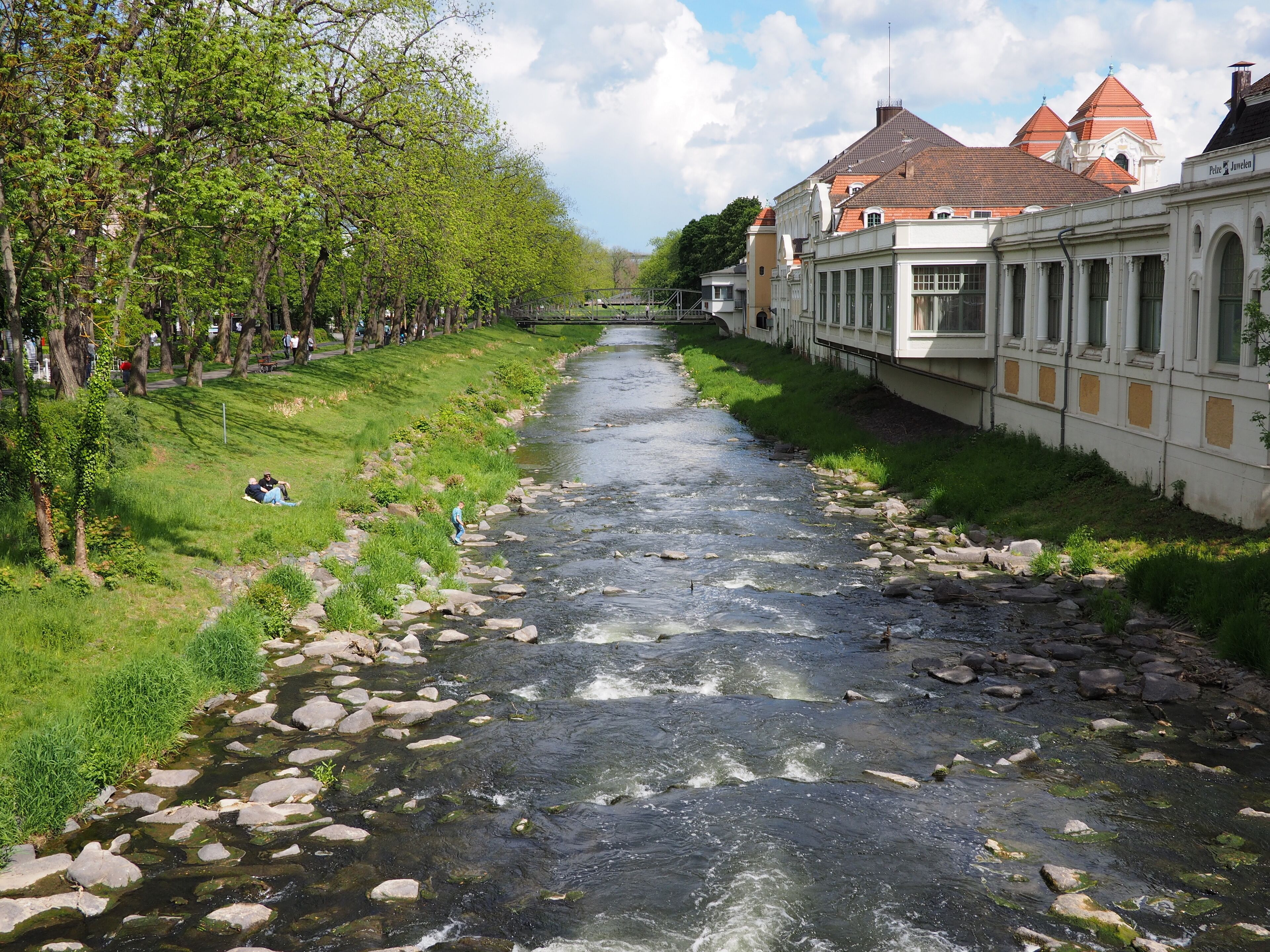 A river with rocks, trees, and buildings along the banks.