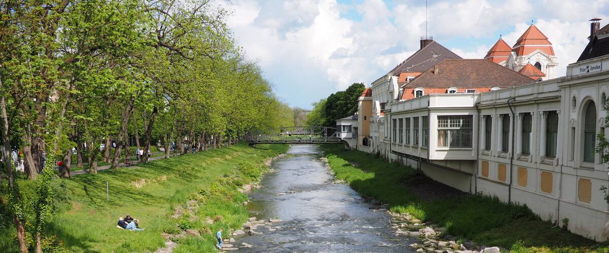 A river with rocks, trees, and buildings along the banks.