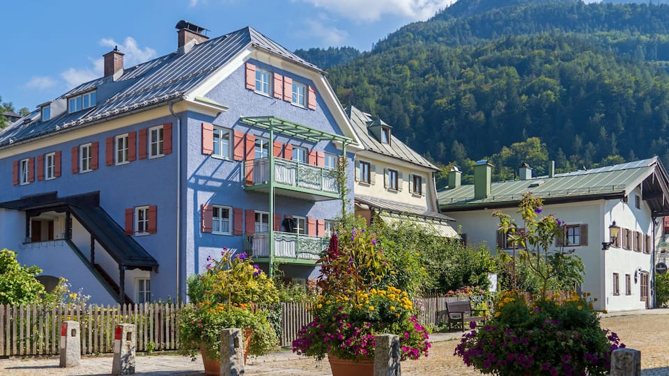 A colorful building with a balcony, surrounded by potted plants and a cobblestone street.