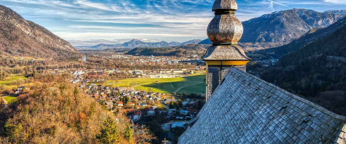 A church with a distinctive onion dome, a town in the valley below, and mountains in the background.