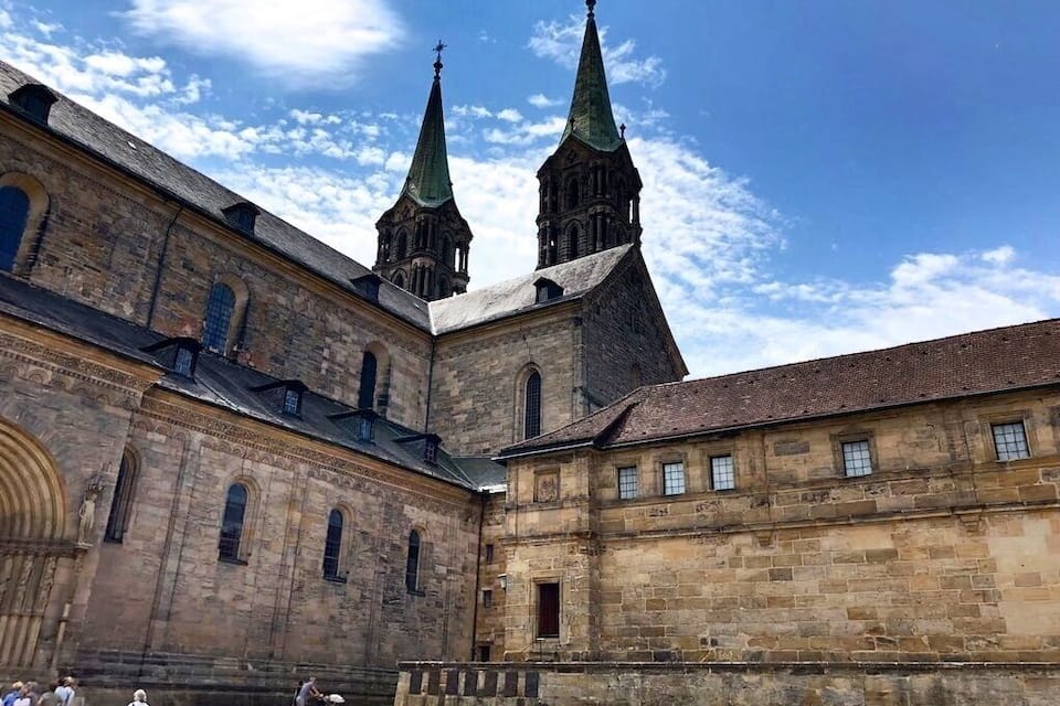 A historic building with two prominent towers and a courtyard.