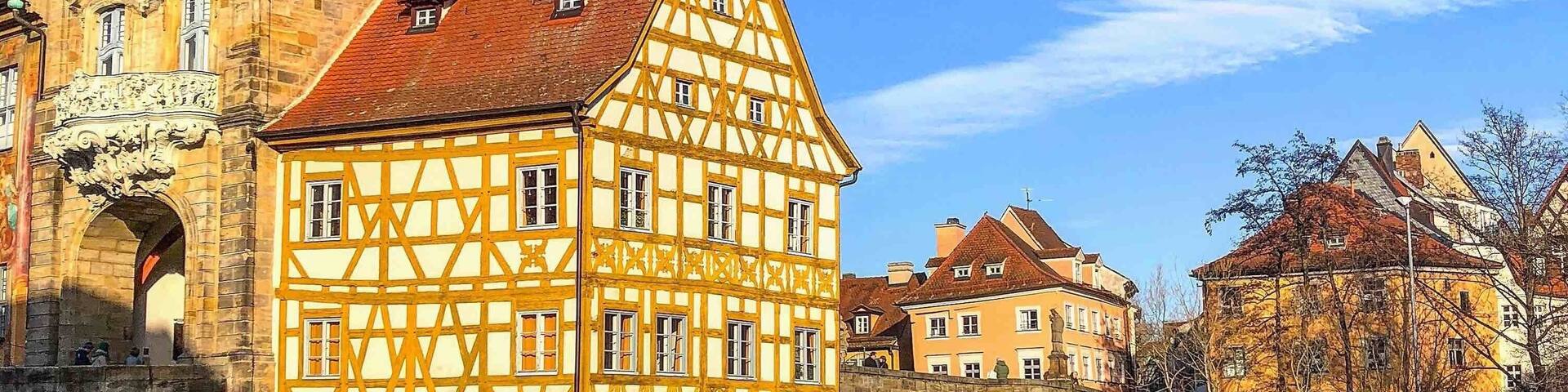 A half-timbered building with a clock tower, a stone bridge, and a river.