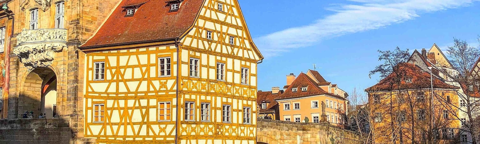 Um edifício em estilo de enxaimel com uma torre do relógio, uma ponte de pedra e um rio.