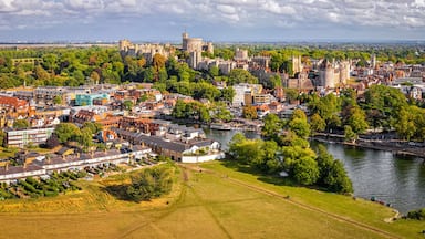 Uma cidade histórica com um castelo, rio e vegetação ao redor.
