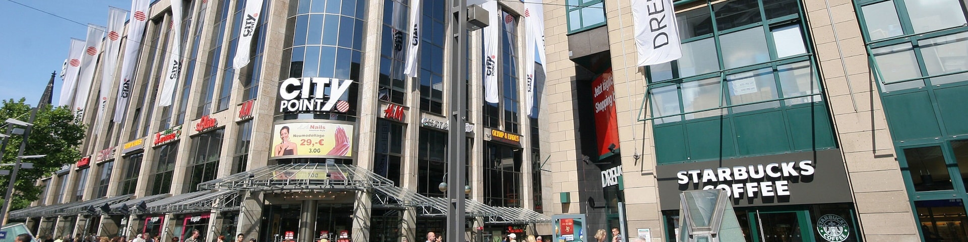CITY POINT building with CITY POINT and H&M signs, a Starbucks Coffee shop, and various other storefronts.