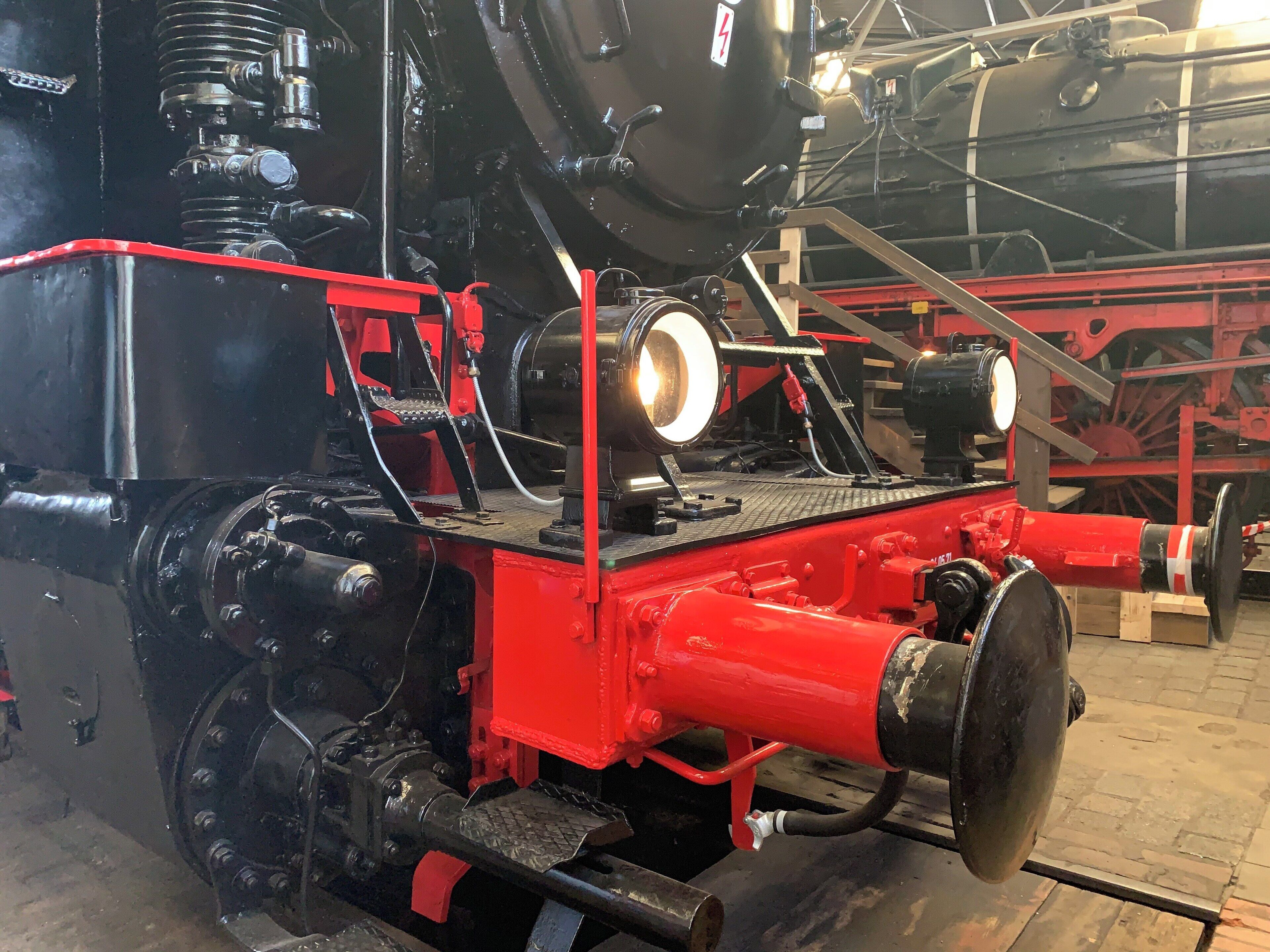 A large, black and red steam locomotive with visible wheels and mechanical components.