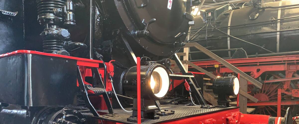 A large, black and red steam locomotive with visible wheels and mechanical components.