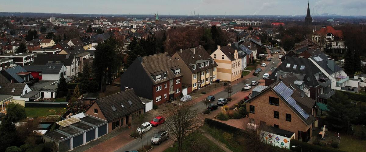 A residential area with houses, streets, and a church spire in the distance.