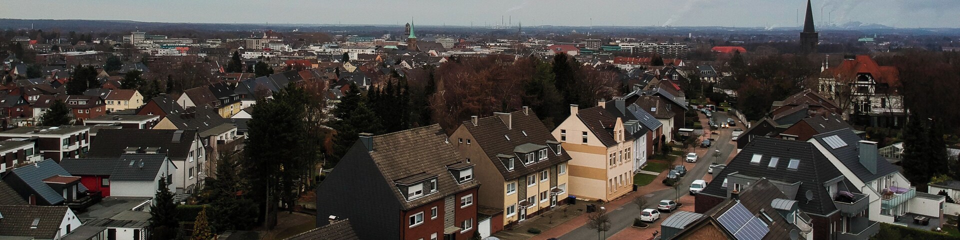 A residential area with houses, streets, and a church spire in the distance.