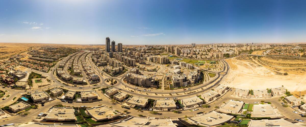 Paisagem urbana com uma rotatória central, áreas residenciais ao redor e paisagem desértica ao longe.
