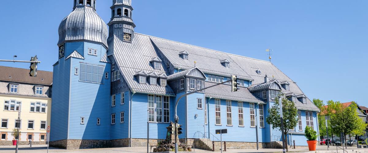 A blue church with two domes and a bell tower.