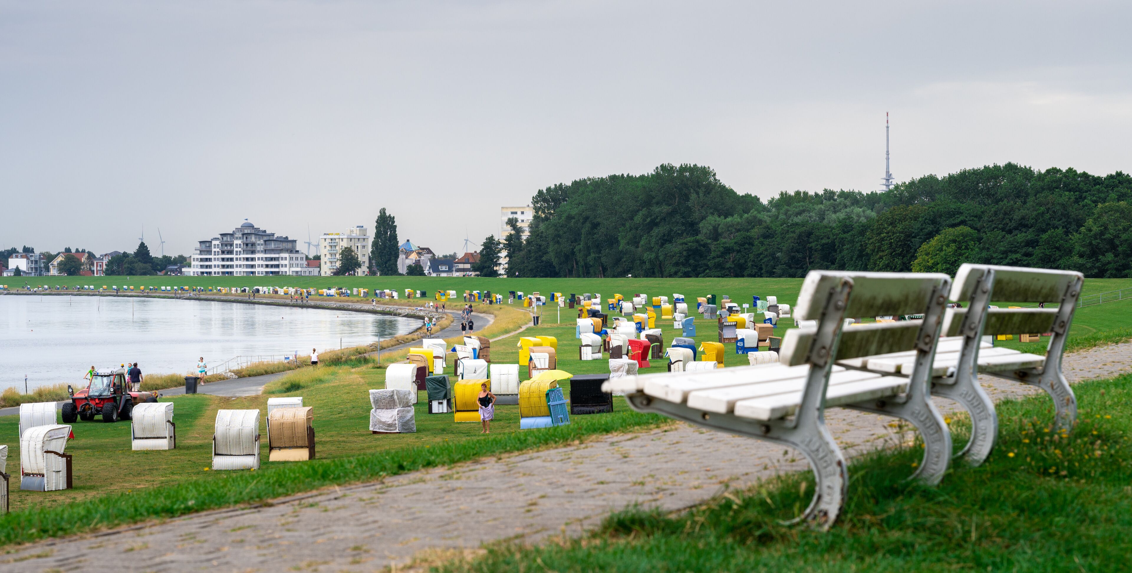 A park with a lake, benches, and a row of colorful mailboxes.