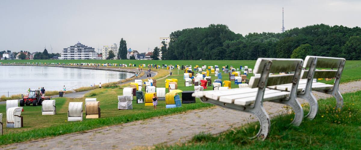 A park with a lake, benches, and a row of colorful mailboxes.