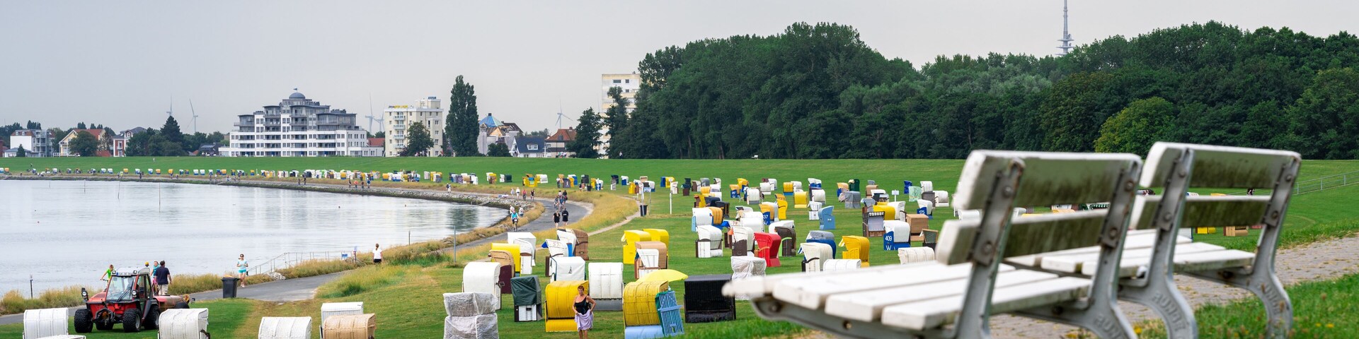 A park with a lake, benches, and a row of colorful mailboxes.