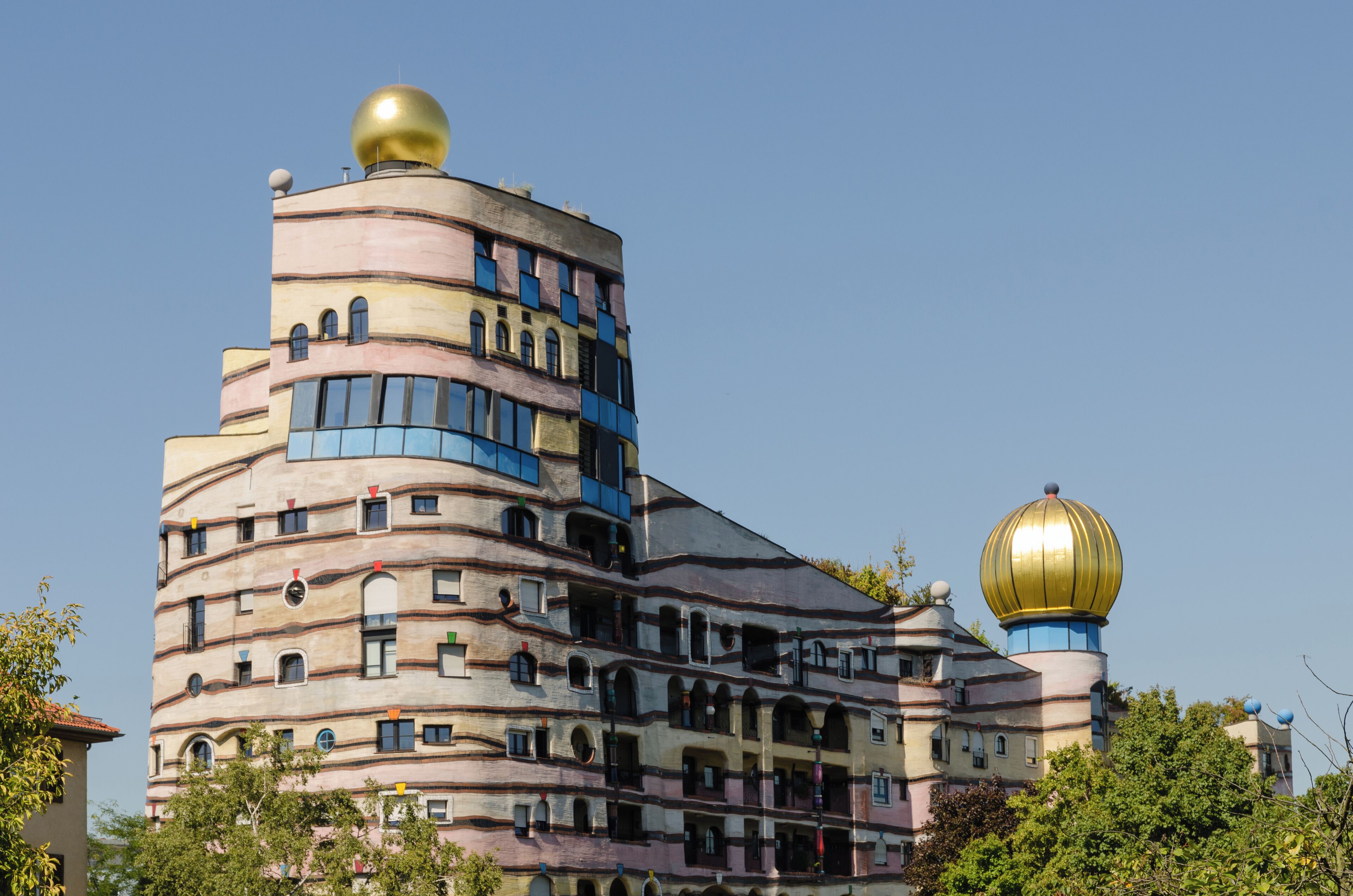 A multi-story building with a distinctive wavy facade and a golden dome.