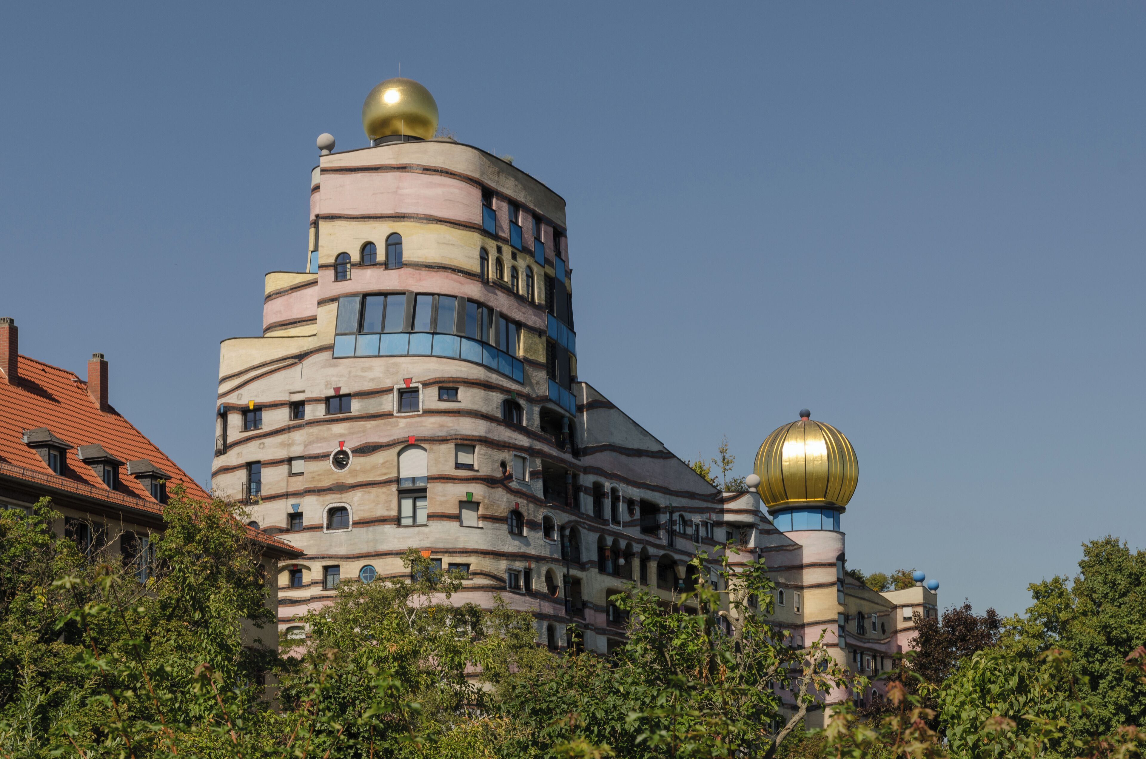 A uniquely designed building with multiple curved levels and golden domes.