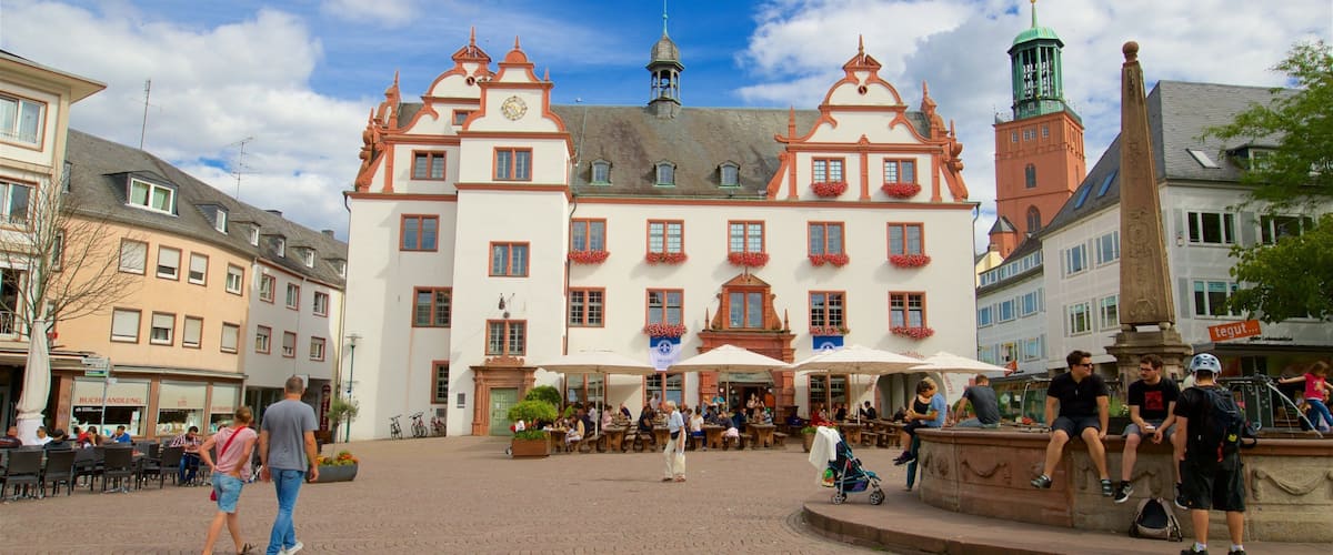 A historic building with ornate architecture, a central fountain, and a cobblestone square.