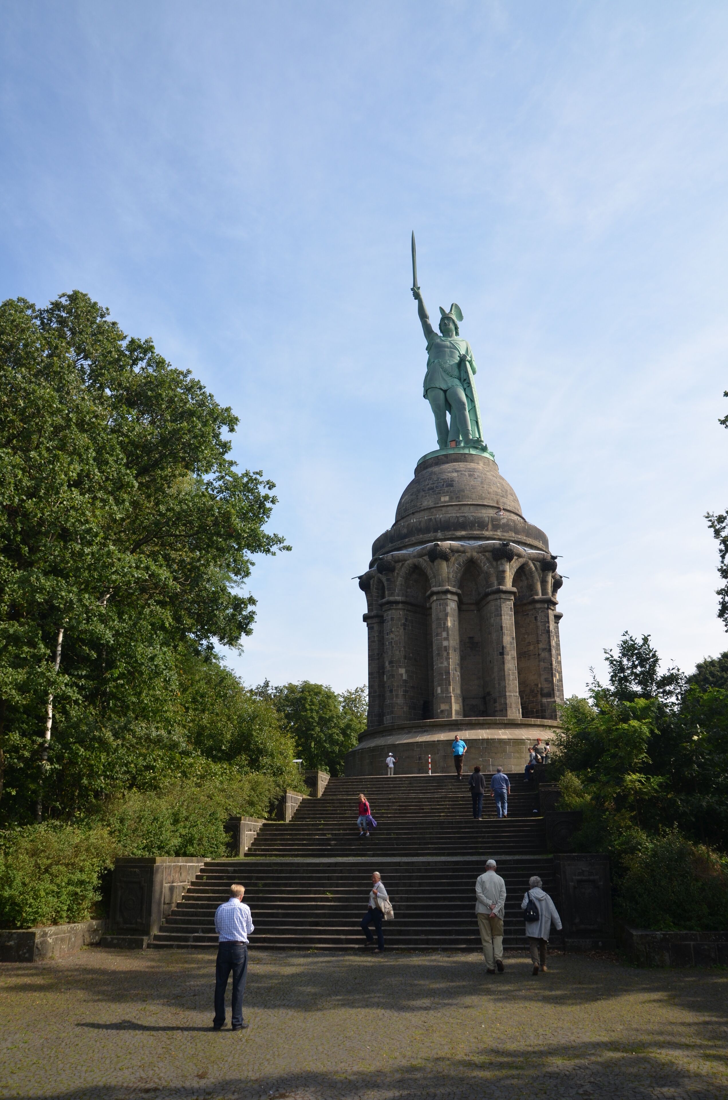 A statue of a figure holding a sword, surrounded by steps and greenery.