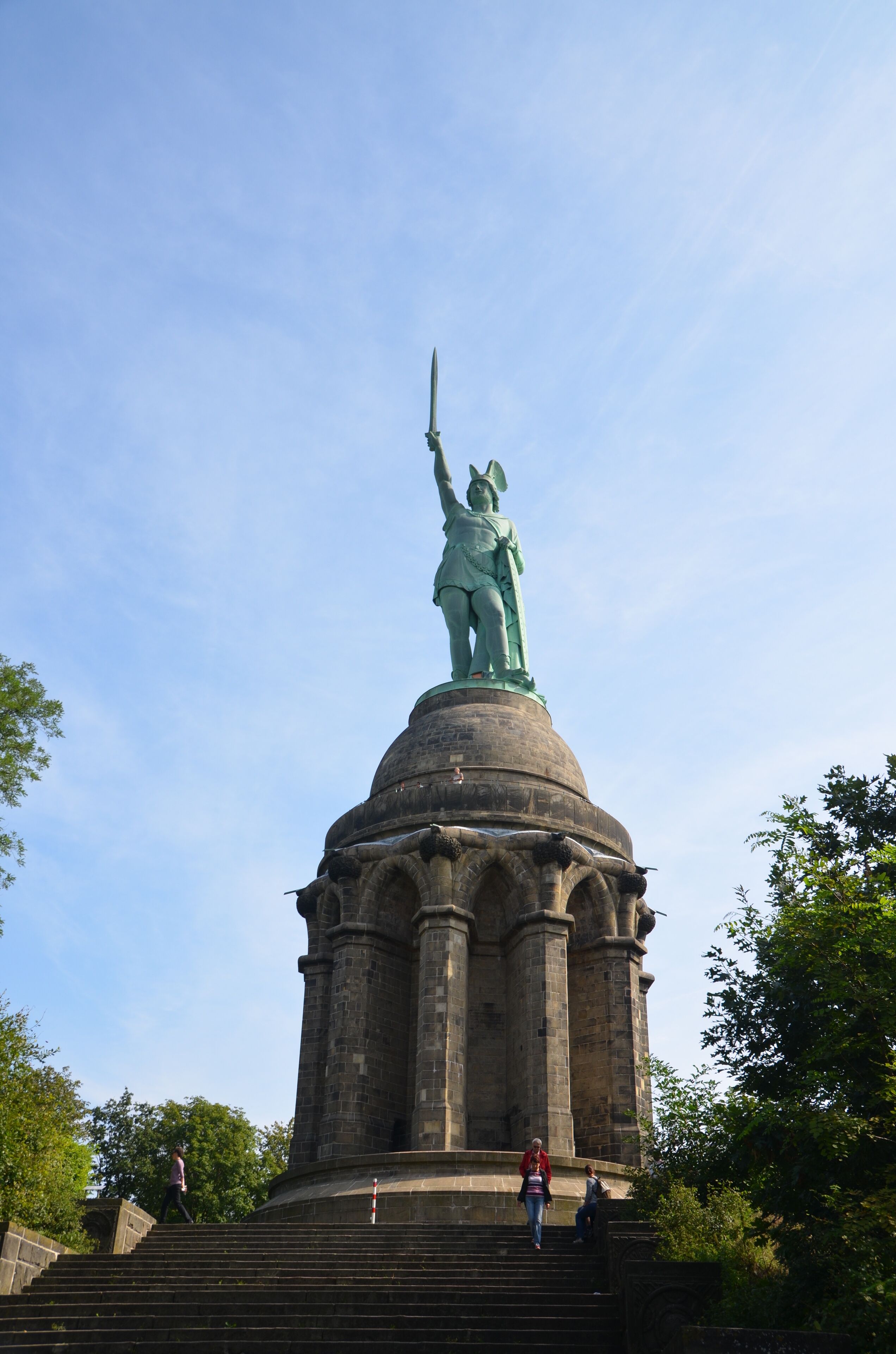 A statue of a woman holding a sword on a stone pedestal with steps leading up to it.