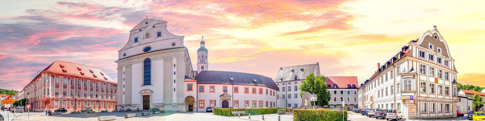 A historic square with a church, a statue, and classic European architecture.