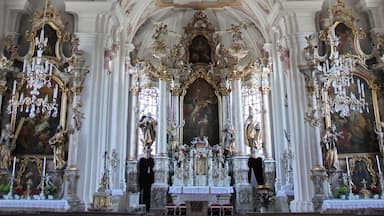 Interior de igreja ornamentado com afrescos elaborados, arcos dourados e um altar central.