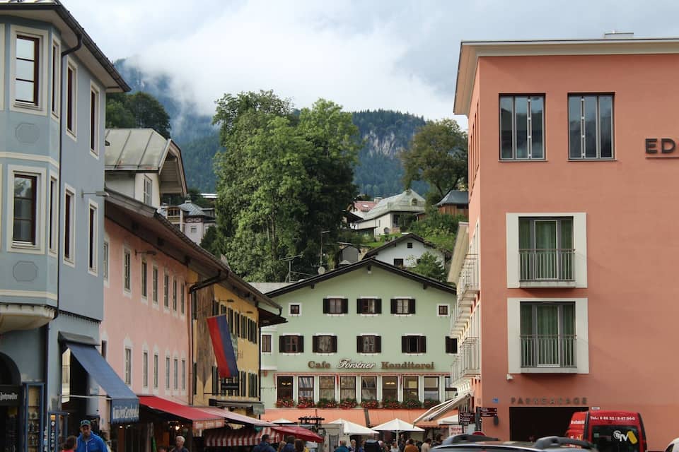 A street with buildings, a cafe, and a mountain in the background.