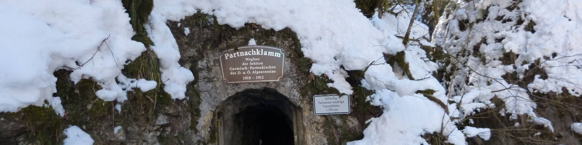 A snow-covered tunnel entrance with a sign indicating it was built between 1910 and 1912.
