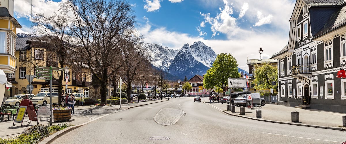 A mountain town street with buildings, cars, and a mountain backdrop.