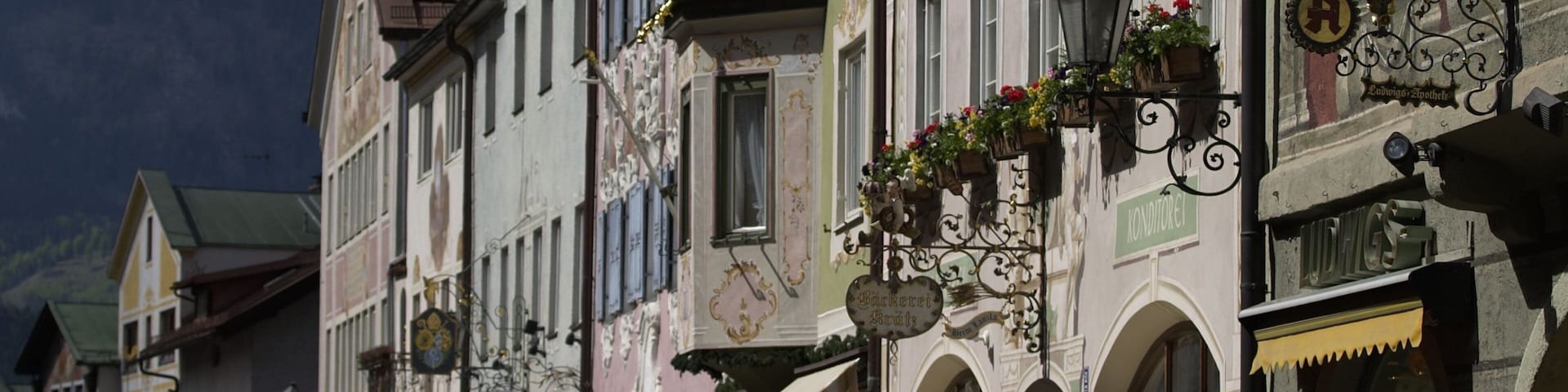 Una calle con arquitectura europea tradicional, que incluye fachadas ornamentadas y macetas con flores.
