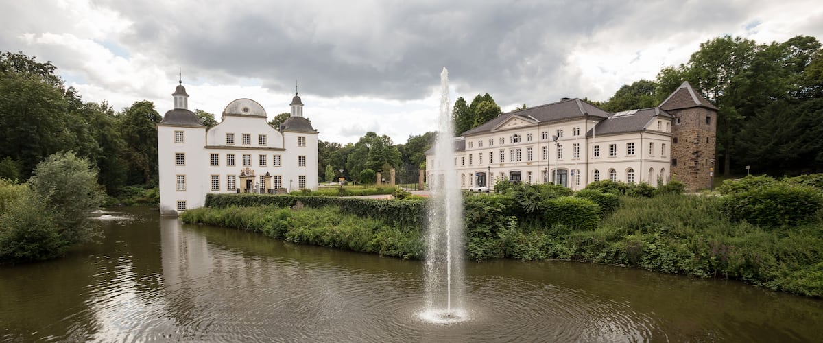 A historic building with a fountain in a garden.