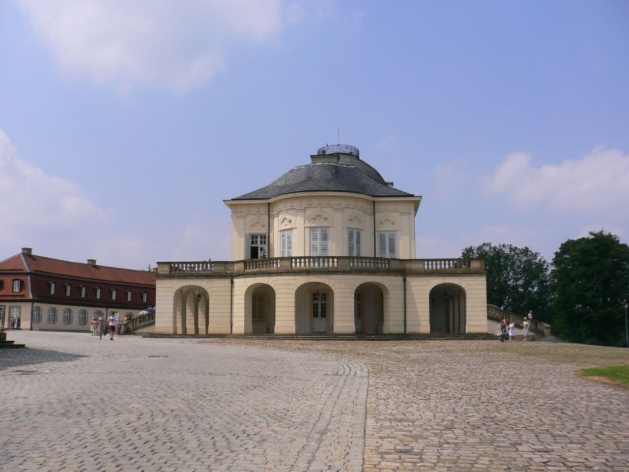 A historic building with a dome and arched windows, surrounded by a cobblestone courtyard.