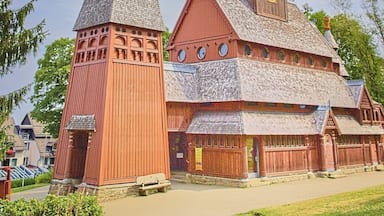 Una iglesia con un campanario alto y una torre más pequeña, rodeada de vegetación.