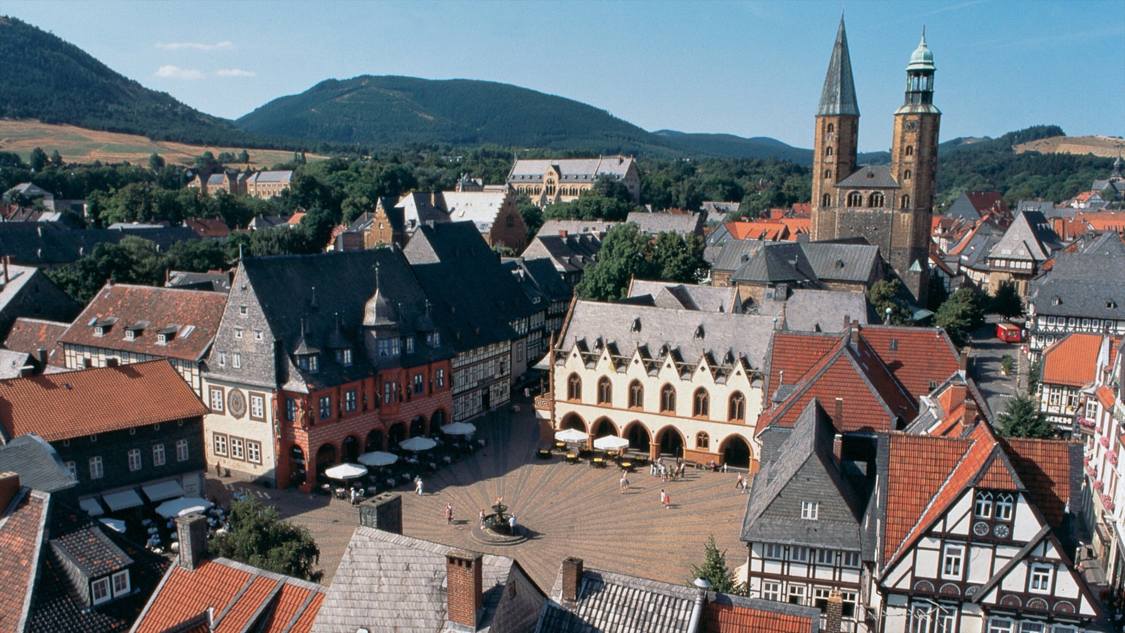 A historic town square with traditional buildings, a church, and a hill in the background.