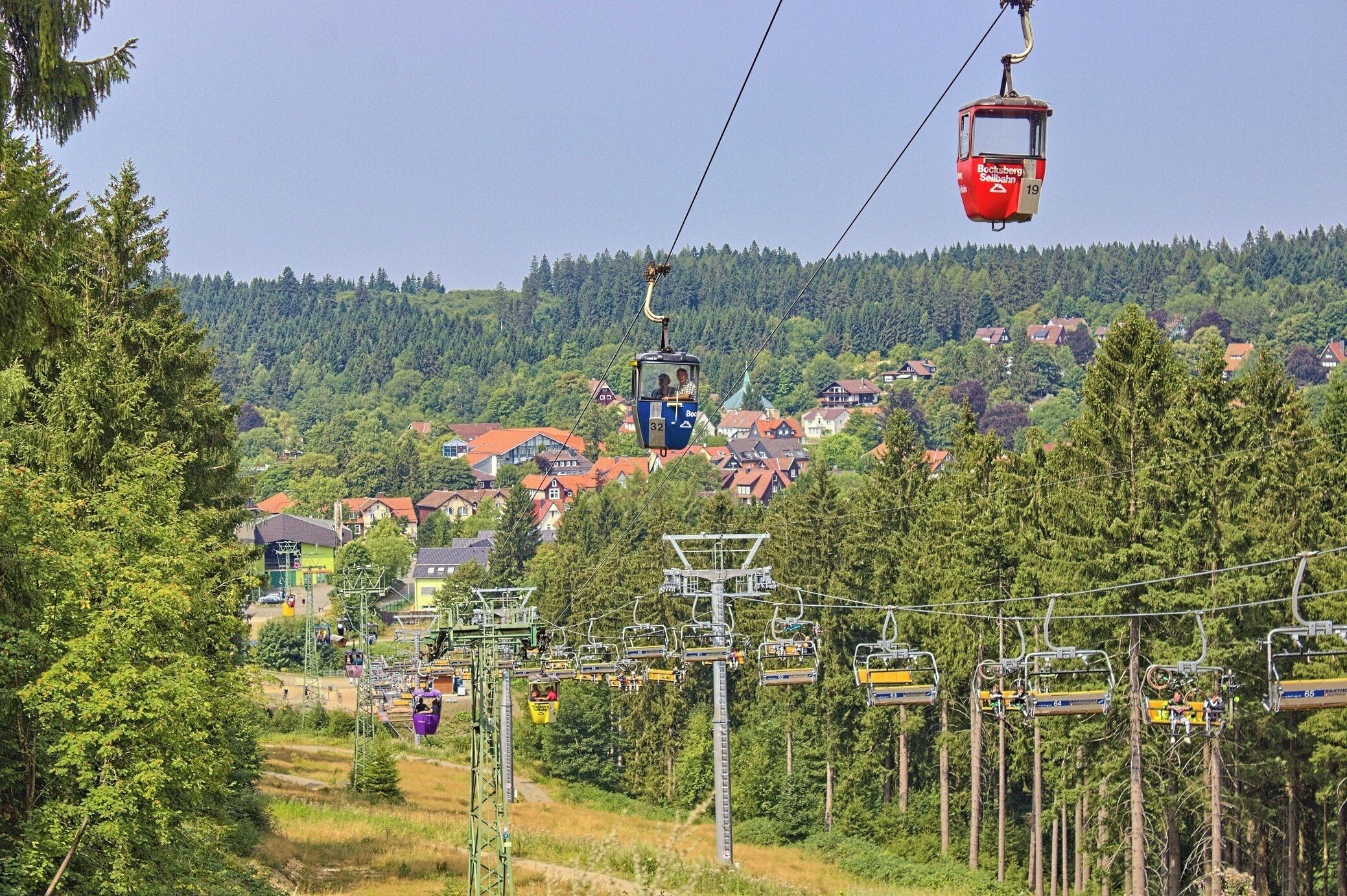 A cable car system with houses and trees in the background.