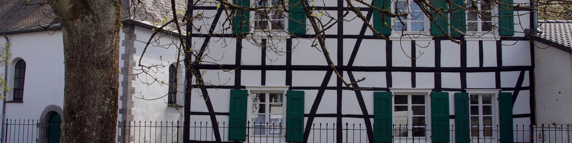Una casa tradicional de entramado de madera con contraventanas verdes y tejado de tejas.