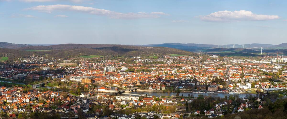 A town with a river, wind turbines, and a bridge.