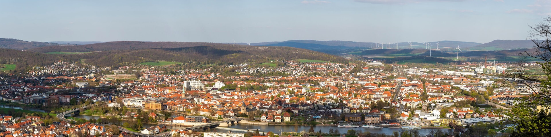 A town with a river, wind turbines, and a bridge.