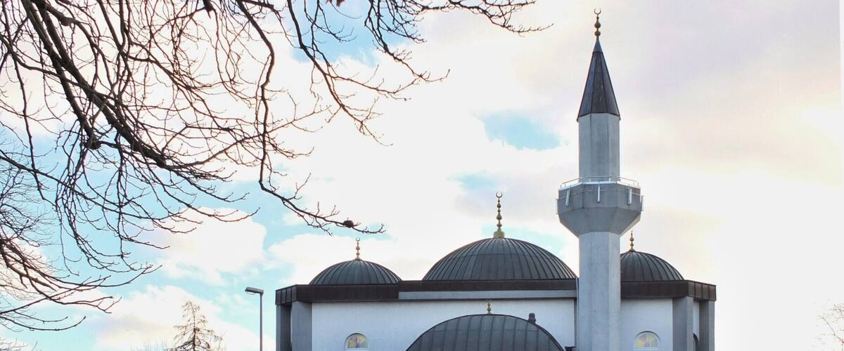 A mosque with three domes and a tall minaret.
