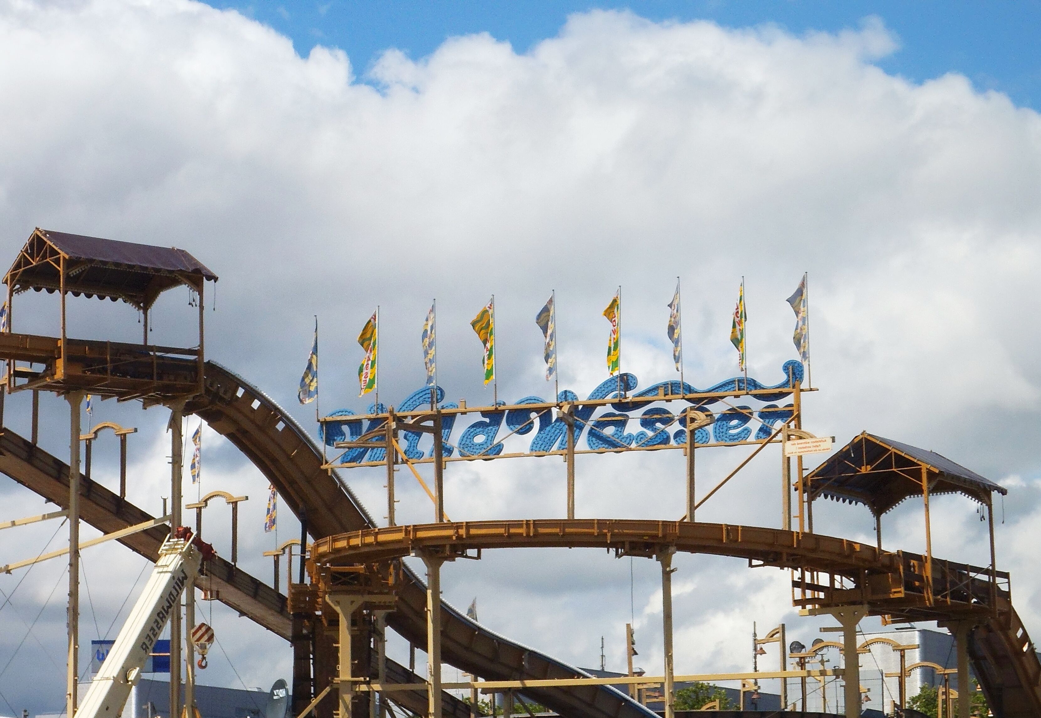 A roller coaster with a sign that reads "Wild West" and multiple flags.